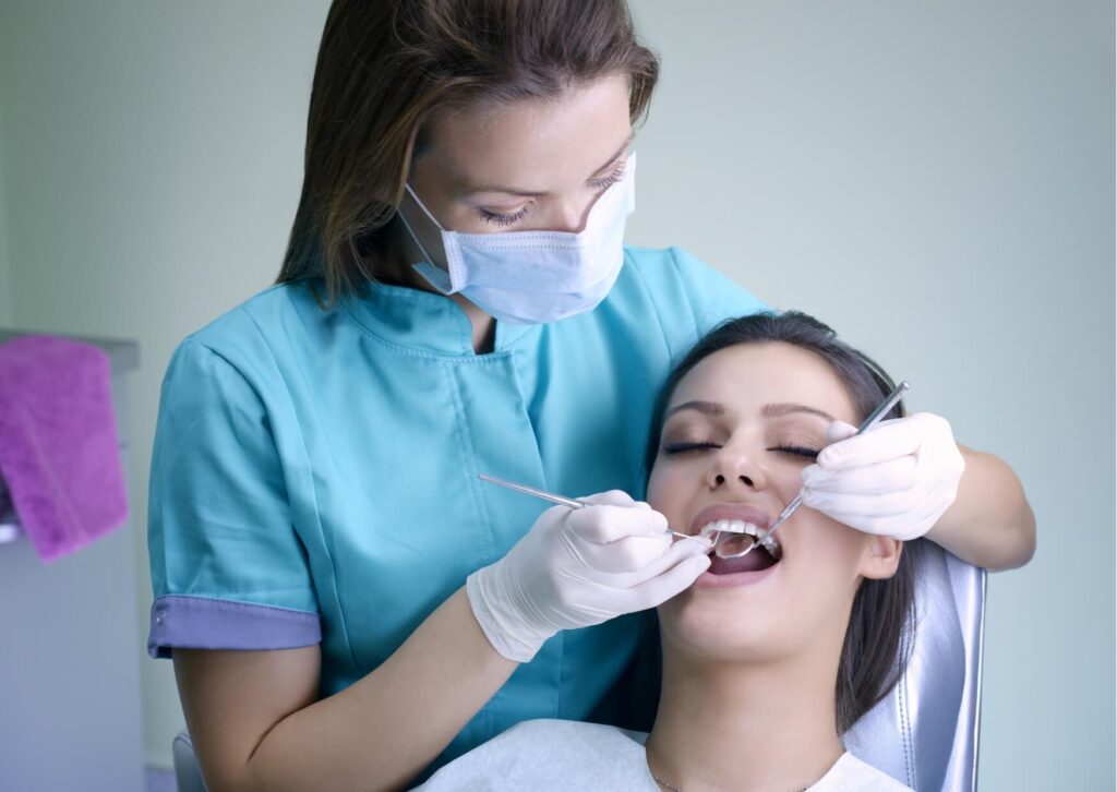 Dentist examining a patient's mouth during a checkup to monitor tooth eruption and ensure permanent teeth are coming in properly.