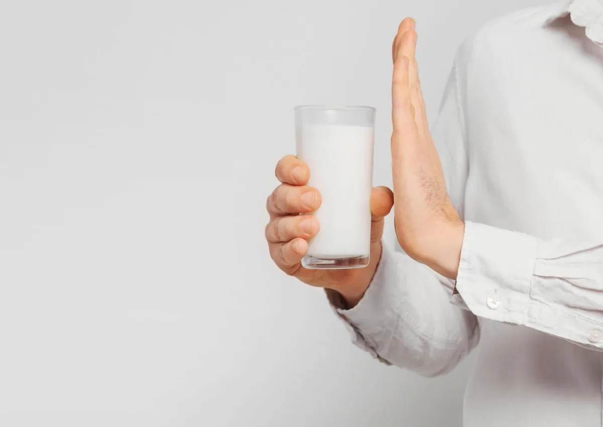 Person avoiding a glass of milk after dental implant surgery as part of post-operative dietary care.