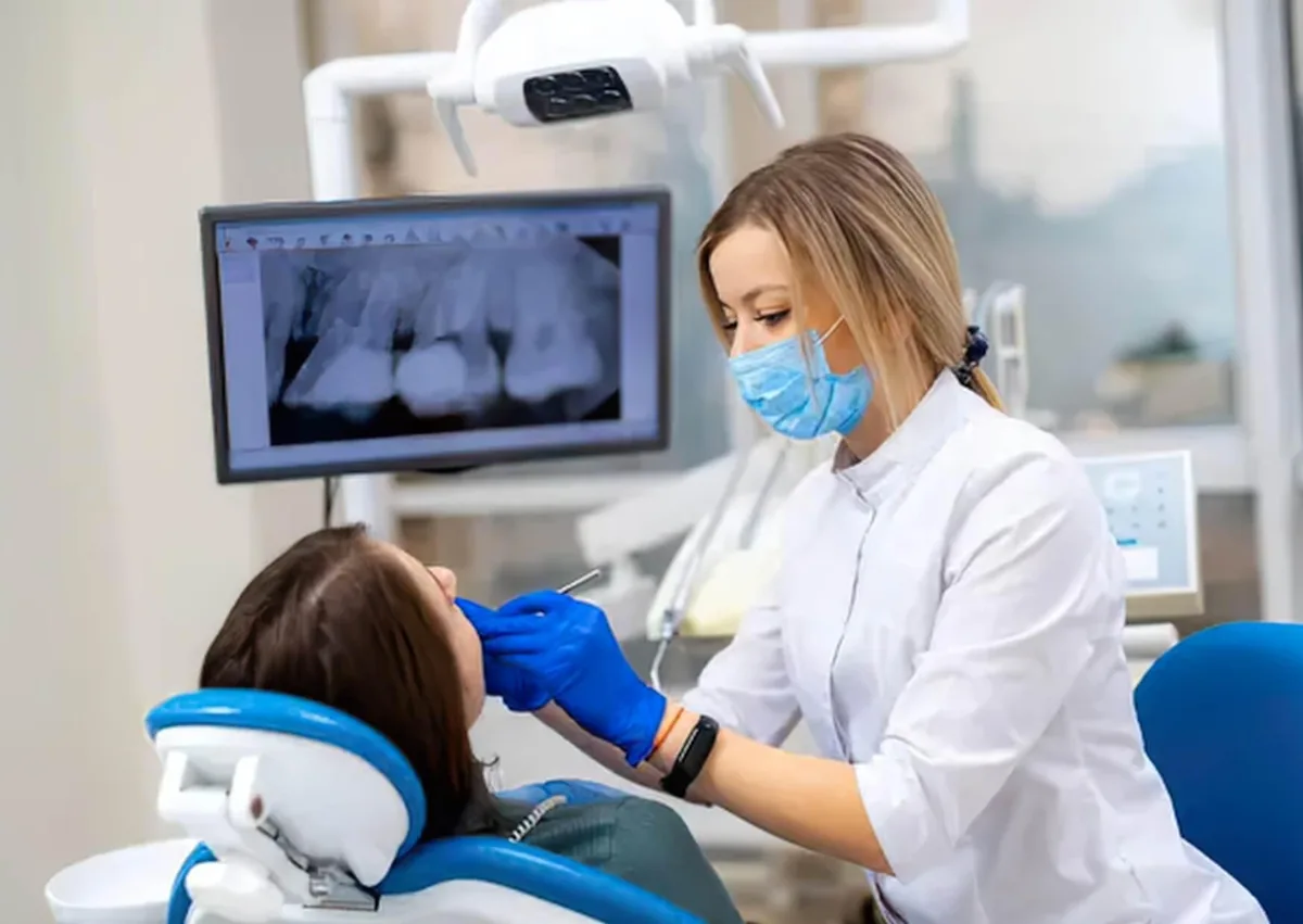 Dentist examining a patient and reviewing dental X-rays to plan affordable dental implant treatment.