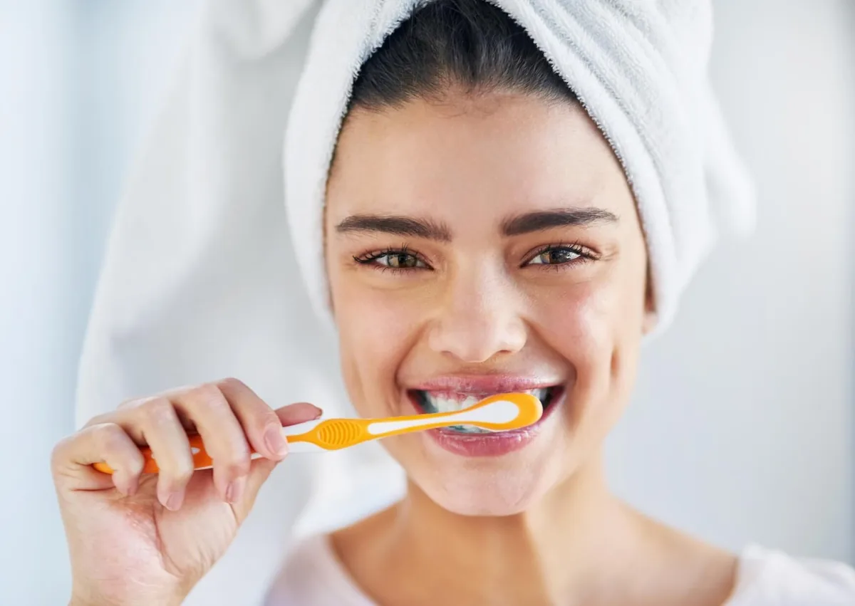 Woman brushing her teeth as part of daily care after teeth bonding treatment.