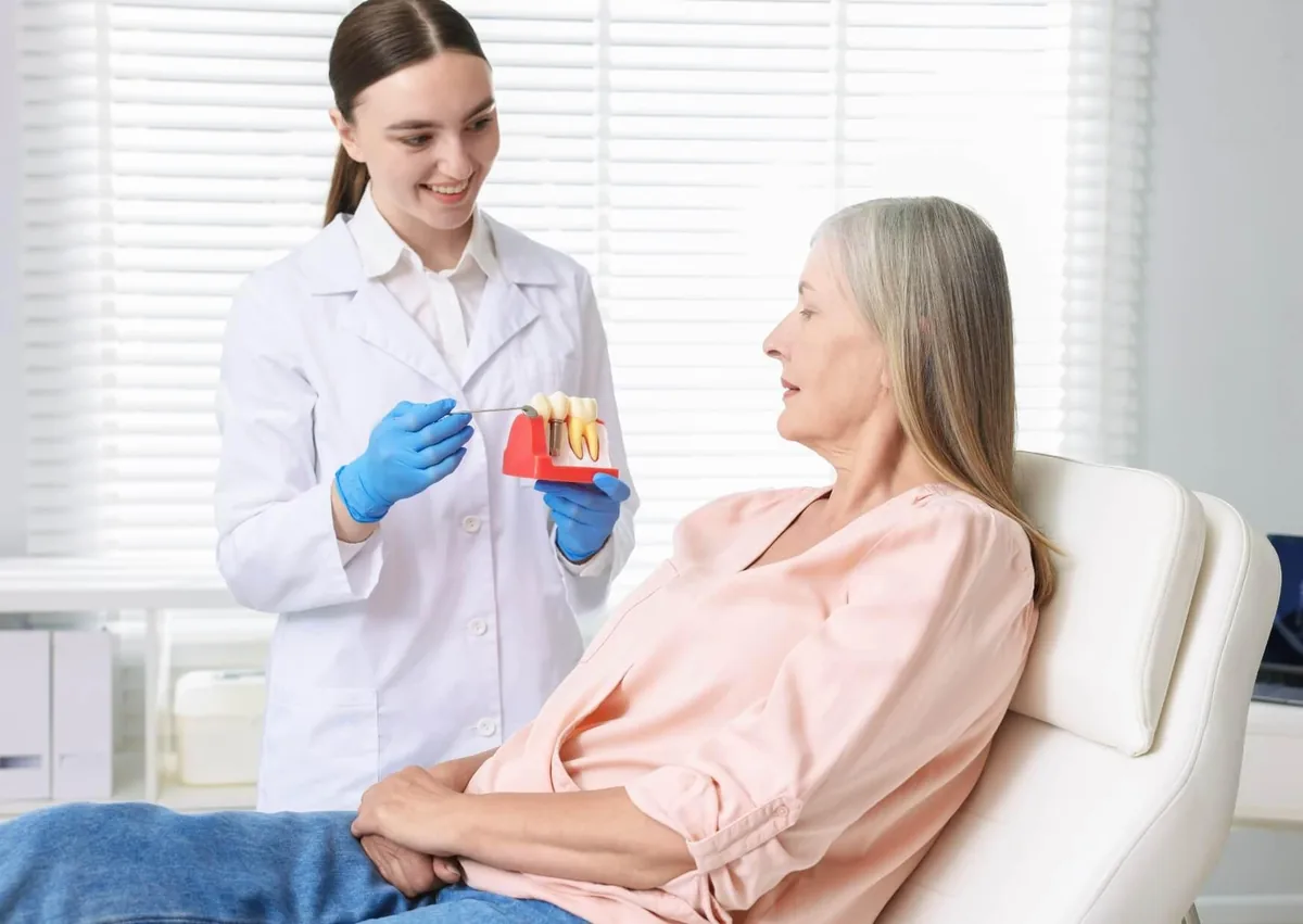 Dentist explaining different types of dental implants to a patient using a dental implant model.